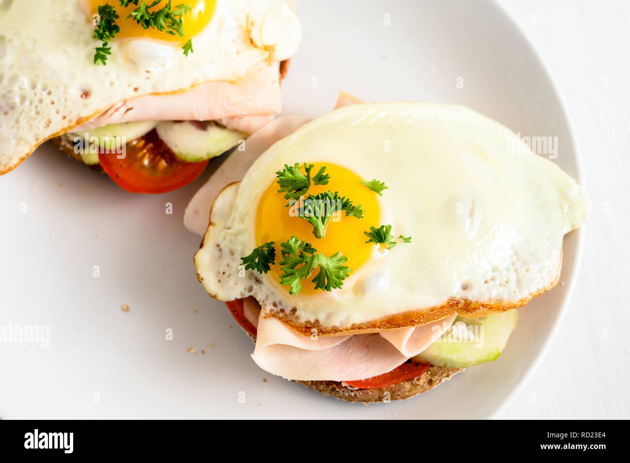 Œuf frit sur du pain complet rouleau avec tomate, concombre et jambon cuit, bon petit déjeuner sain sur un tableau blanc, copy space, high angle view de ab Banque D'Images