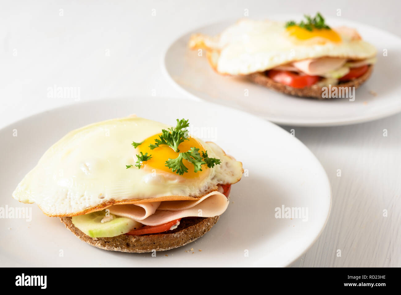 Œuf frit sur du pain complet rouleau avec tomate, concombre et jambon cuit, bon petit déjeuner sain sur un tableau blanc, copie, espace étroit, de mise au point sélectionnée Banque D'Images