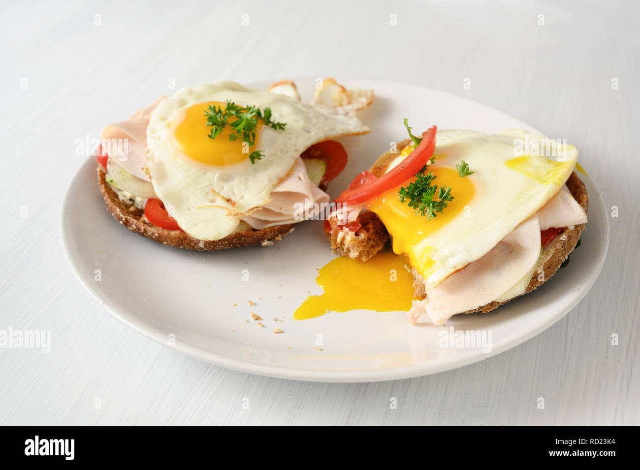 Œuf frit à l'œuf sur du pain complet roule avec tomate, concombre et jambon cuit, bon petit déjeuner sain sur un tableau blanc, copy space, séle Banque D'Images