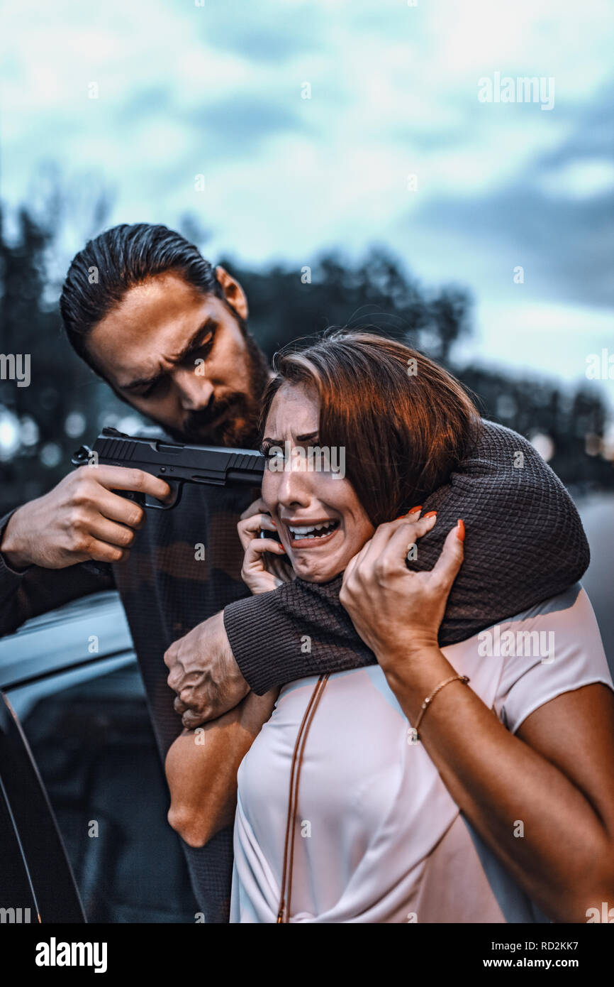 Un dangereux criminel, menacer une jeune femme avec fusil pour lui dire où est son petit ami. Banque D'Images