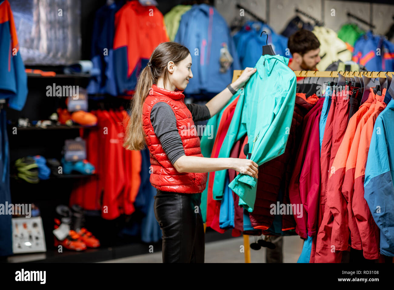 Jeune femme de choisir des vetements d hiver prendre doudounes sur le crochet dans le magasin de sport Photo Stock Alamy