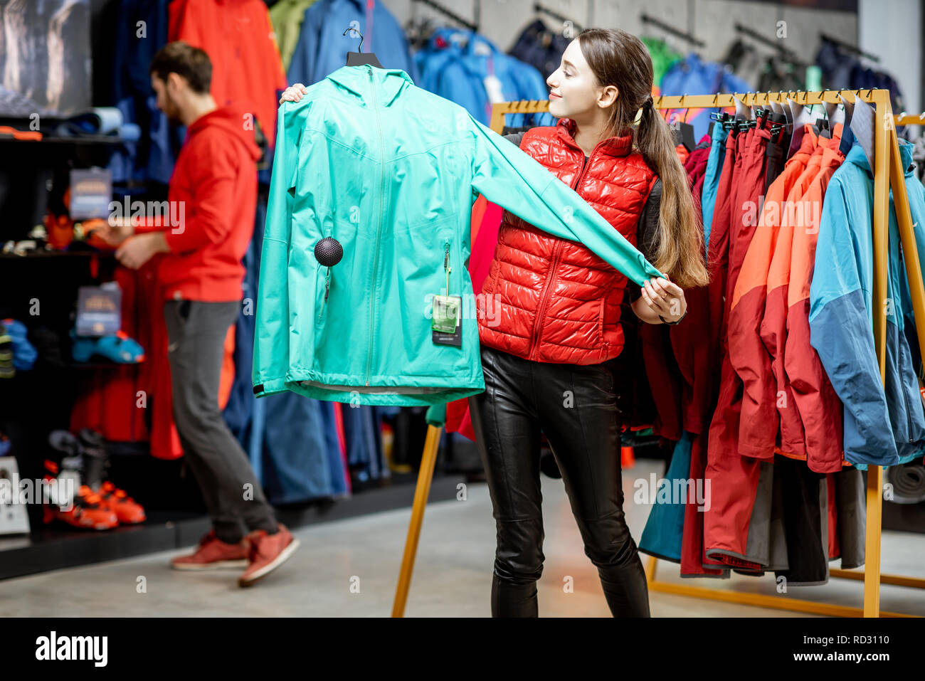 Jeune femme de choisir des vêtements d'hiver Veste windbreaking essayer dans le magasin de sport Banque D'Images