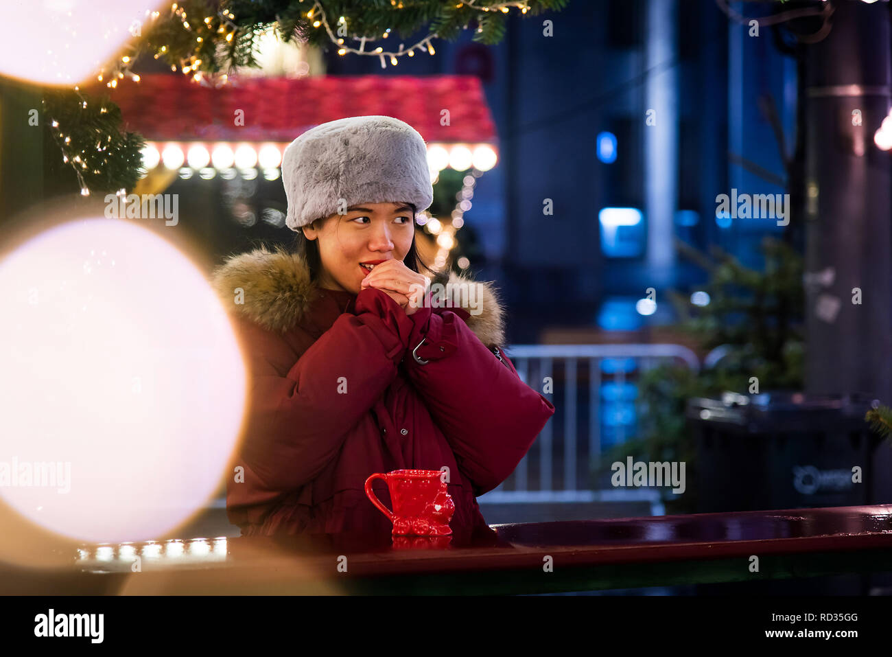 Femme l'échauffement avec un verre en plein air sur une nuit d'hiver Banque D'Images