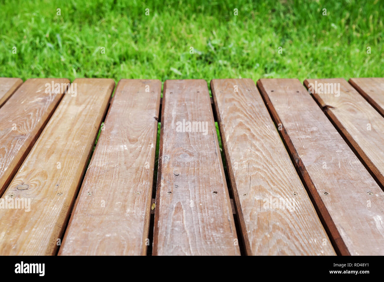 Vue en perspective d'une table en bois sur la pelouse avec de l'herbe bien verte, parc naturel de fond. Photo en gros plan avec selective focus Banque D'Images