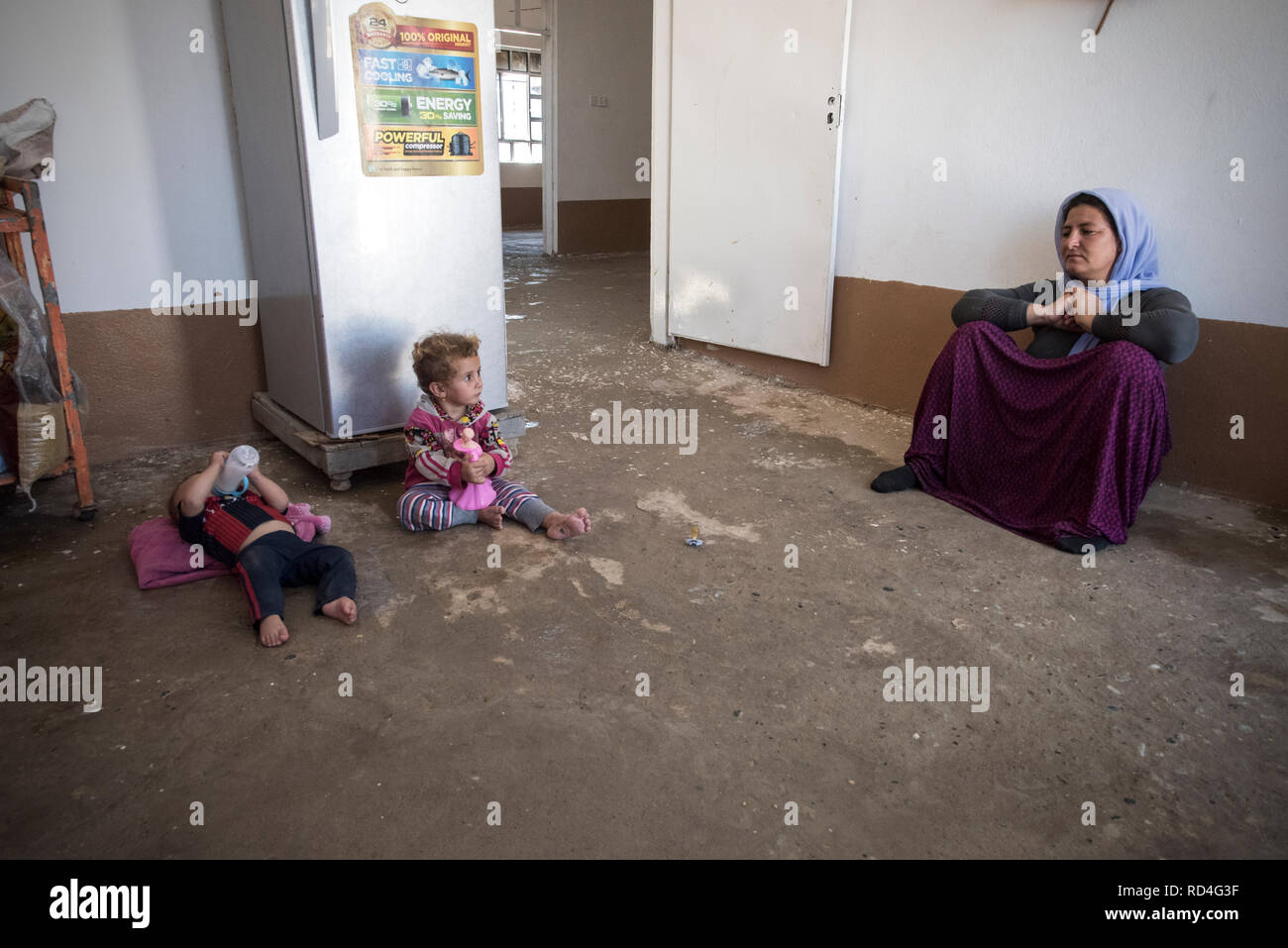 Vu une femme avec ses deux fils, à la Chambre, ils ?ve de retour à. On estime que l'État islamique a tué 3 000 à 5 000 hommes yézidis. Comme pour les femmes, ils ont été enlevés, à l'esclavage sexuel et forcées de se convertir à la religion musulmane. En août 2014, l'État islamique capturé Sinjar, la ville principale de la population Yazidis en Iraq. Maintenant, avec la ville en ruines, de l'Iraq de l'Organisation des Nations Unies et ONU-Habitat ont commencé un programme de réhabilitation urbaine en grande partie financée par le gouvernement de l'Allemagne. Ce programme utilise les gens de la région de reconstituer les ménages plus endommagées. Banque D'Images