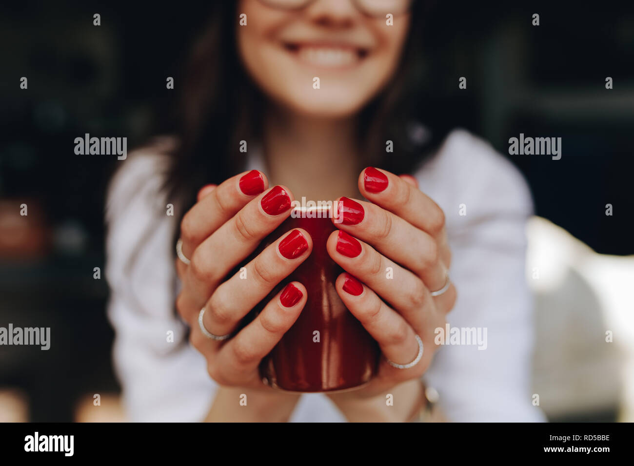 Close up of woman mains tenant une tasse de café. Femelle avec tasse de café assis au café. Se concentrer sur les mains avec du café. Banque D'Images