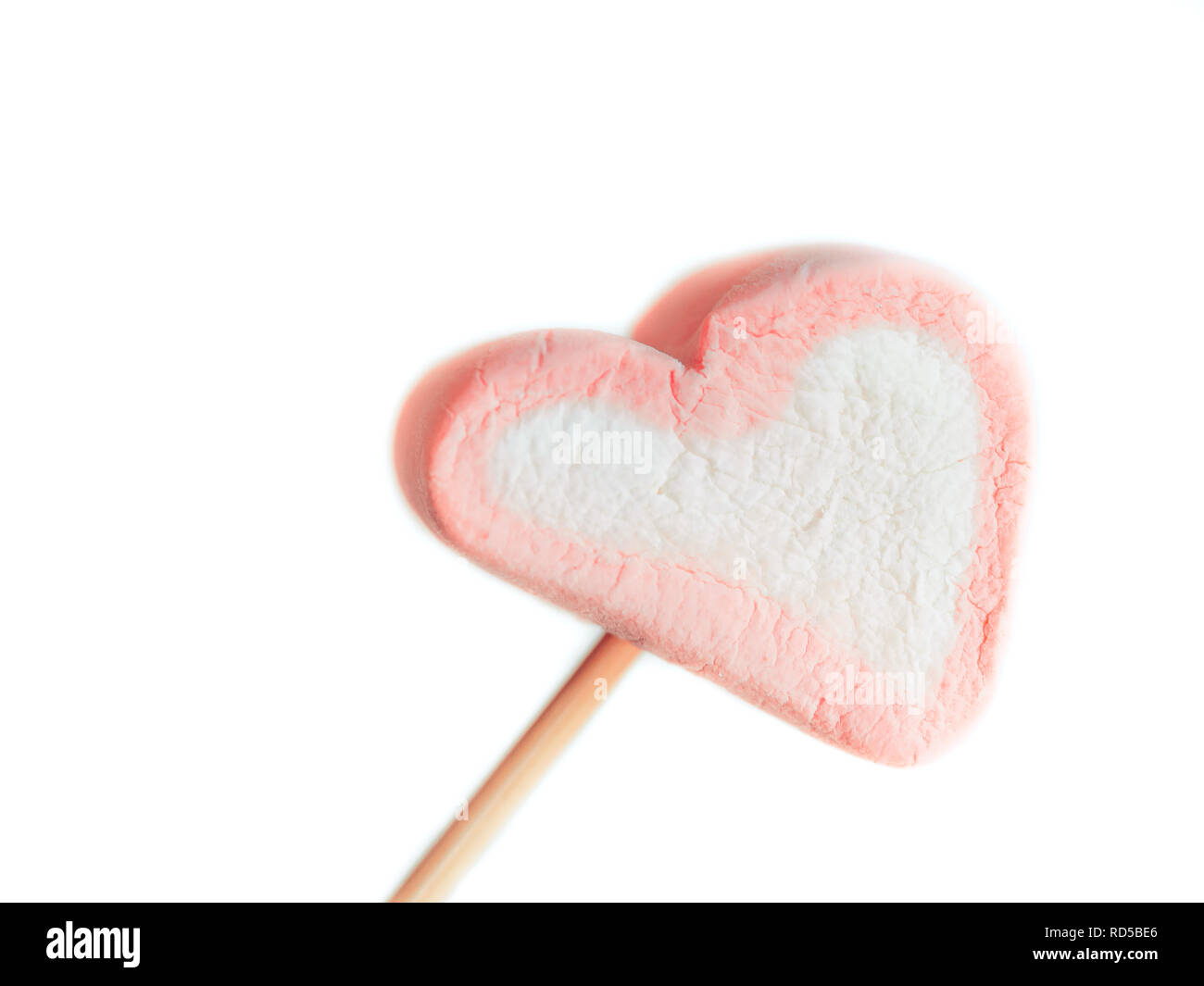 Sur une brochette de guimauve rose close up fond blanc, un coeur des guimauves sur un bâton prêt à fry, bonbons en forme de cœur de guimauve. V Banque D'Images