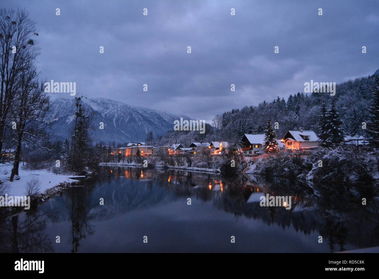 Petites maisons couvertes de neige et feux d'chtistmas dans le pittoresque Bad Goisern, Hallstatt. La tombée de la vue depuis la rivière. Banque D'Images