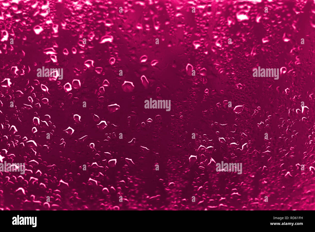 Un contraste élevé photo de gouttes de pluie sur une fenêtre avec verre couleur rose rougeâtre vif Banque D'Images