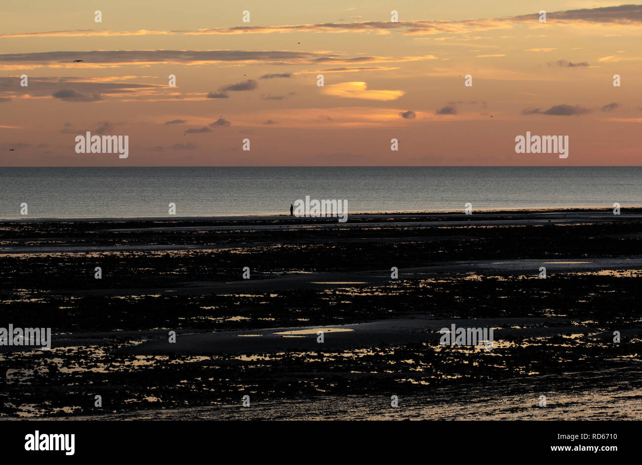 Personne seule en silhouette sur une plage au coucher du soleil Banque D'Images