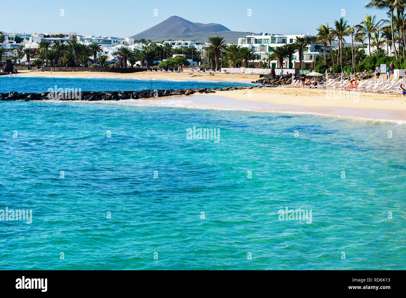 Dans les eaux turquoise de la plage de Las Cucharas, Lanzarote, îles Canaries. Vue sur la mer, plage de sable et les montagnes, selective focus Banque D'Images