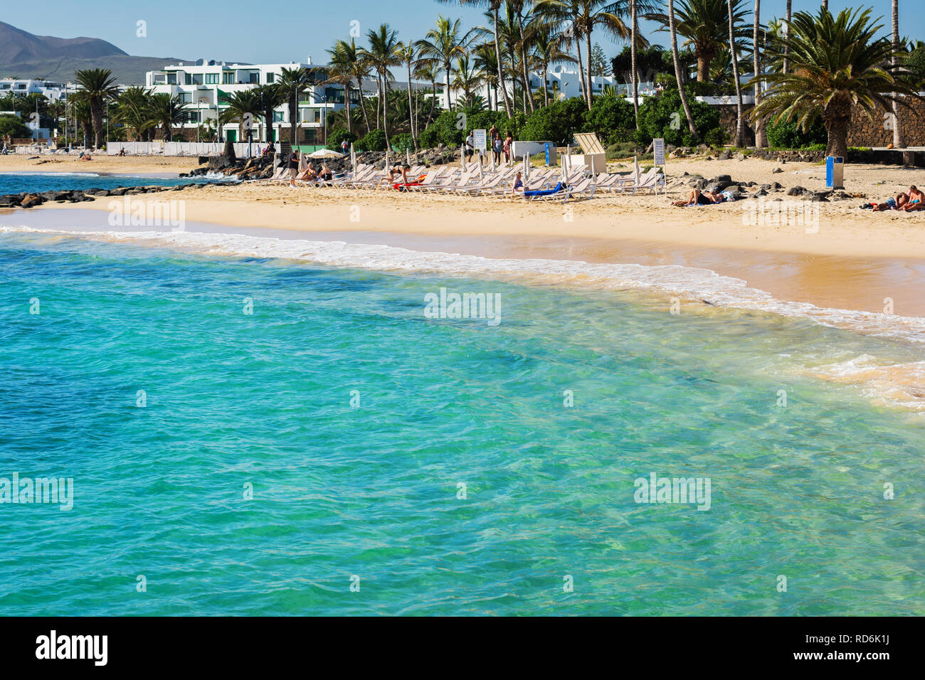 Dans les eaux turquoise de la plage de Las Cucharas, Lanzarote, îles Canaries. Vue sur la mer, plage de sable et rochers, selective focus Banque D'Images