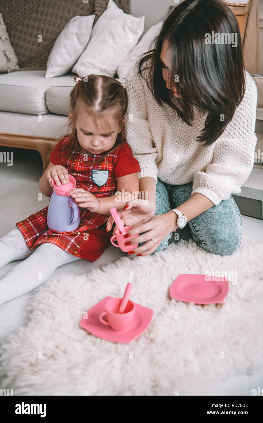 Heureux famille aimante. Mère et sa fille girl jouer plateau-parti et boire du thé de tasses dans la chambre des enfants. Drôle de maman et belle enfant s'amusant à l'intérieur Banque D'Images