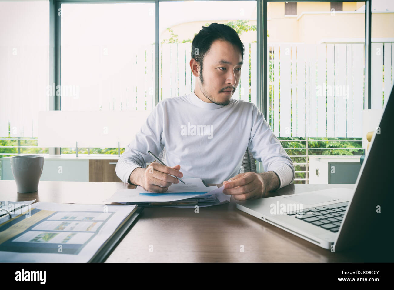 Asian businessman manager smart casual avec faire son travail travail avec ordinateur portable et rapport d'entreprise et assis sur une chaise dans Manager. Banque D'Images