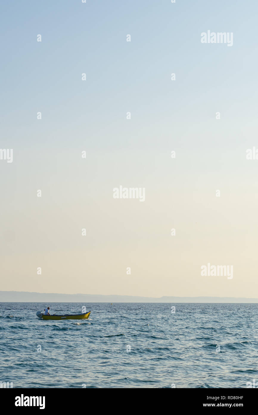 Jaune petit bateau motorisé avec un homme navigue dans la mer ouverte. Banque D'Images