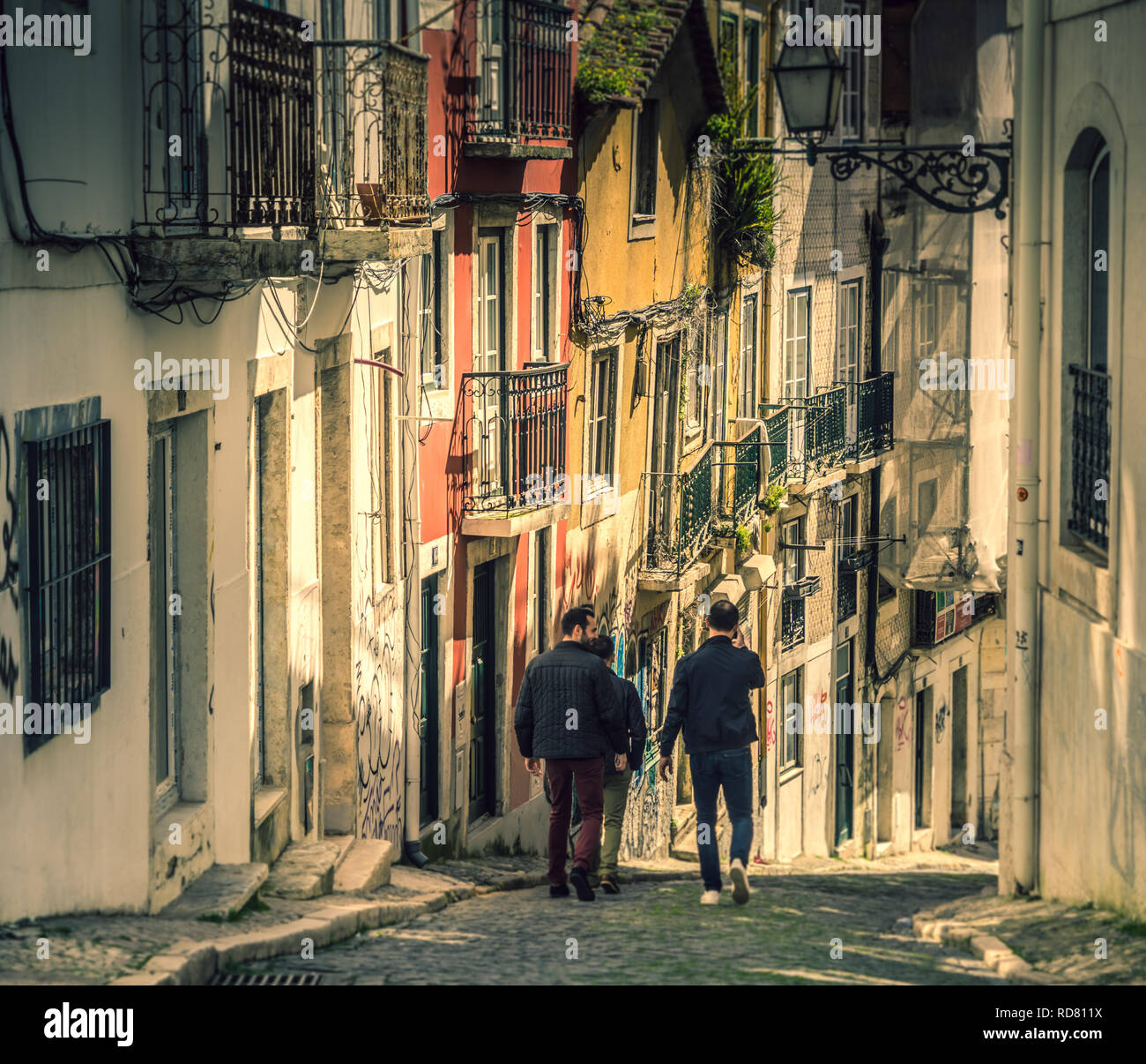 Trois hommes descendant une rue escarpée dans le quartier Bairro Alto de Lisbonne, Portugal. Banque D'Images
