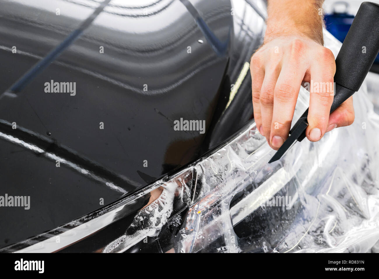 Spécialiste de la mise en film d'aluminium ou de vinyle voiture. Film protecteur sur la voiture. Appliquer un film de protection à la voiture avec des outils pour travailler. Location Banque D'Images