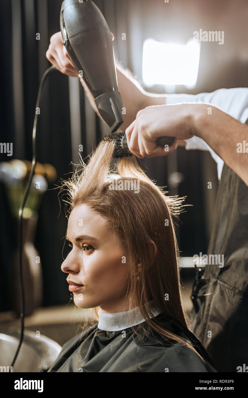 Cropped shot de coiffeur cheveux séchage de belle jeune femme en instituts de beauté Banque D'Images