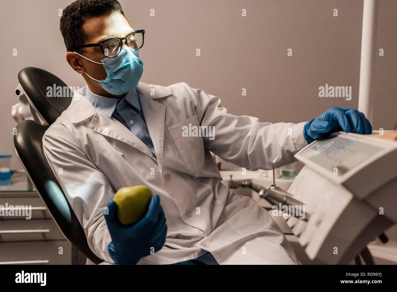 African American dentiste dans lunettes et masque holding apple Banque D'Images