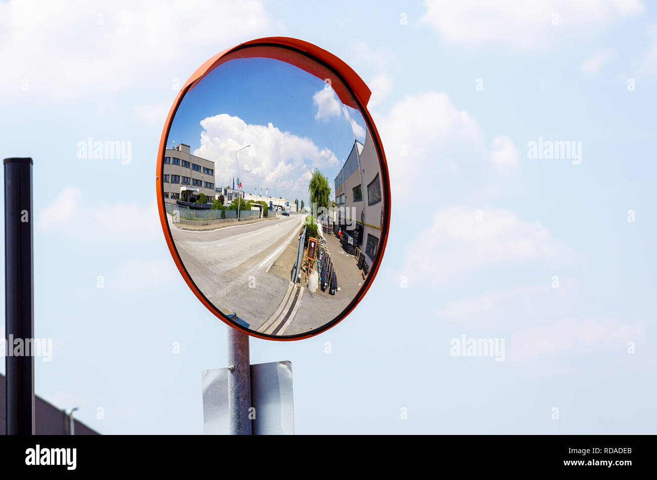 Miroir convexe d'extérieur coffre accroché sur mur avec la réflexion d'un point de vue des routes urbaines de voitures stationnées le long de la rue par des immeubles d'habitation. Banque D'Images