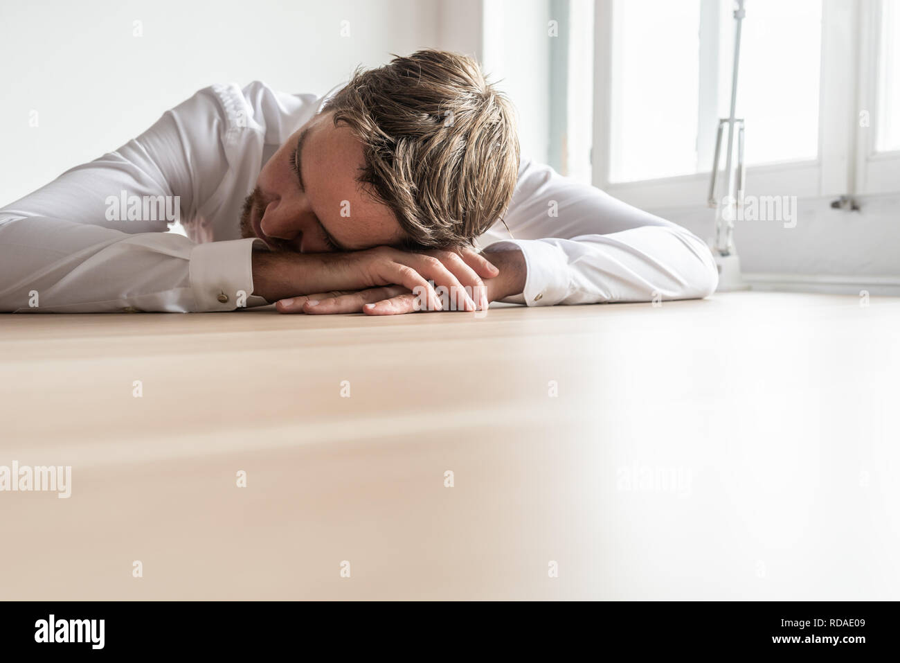 Homme d'affaires fatigué reposant sa tête sur ses mains, assis à un bureau en bois. Avec l'exemplaire de l'espace sur la partie inférieure de l'image. Banque D'Images
