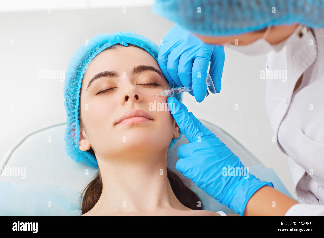 Face à l'injection de beauté pour les femmes. Un cosmetologist fait une injection pour une jeune femme dans un centre de beauté. Banque D'Images