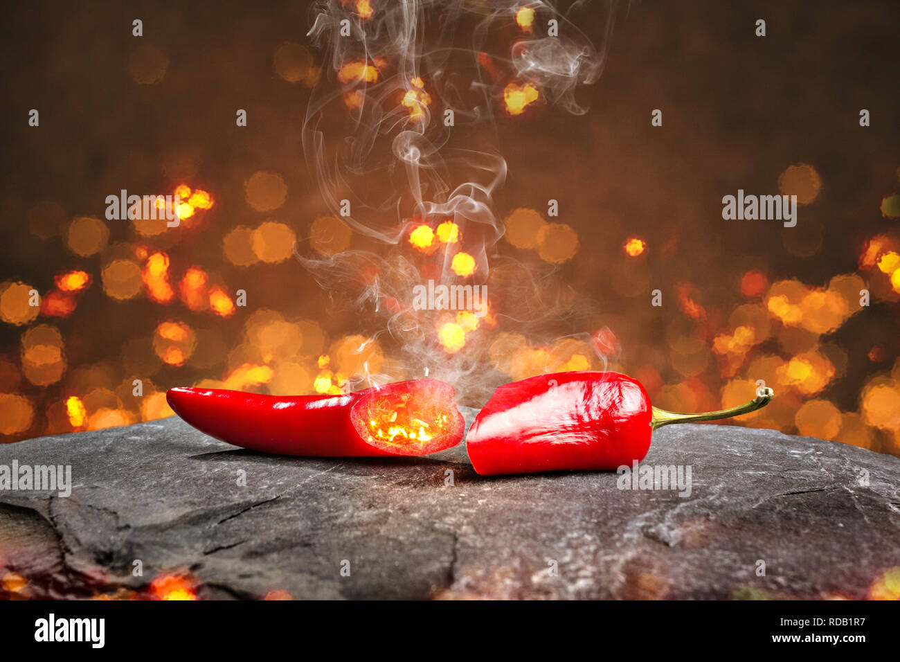 Hot chili pepper entouré de braises et de fumée Banque D'Images