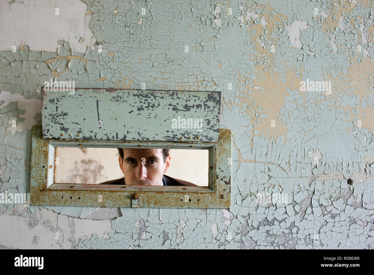 Portrait of a young woman à travers un trou dans un mur d'un bâtiment abandonné. Banque D'Images