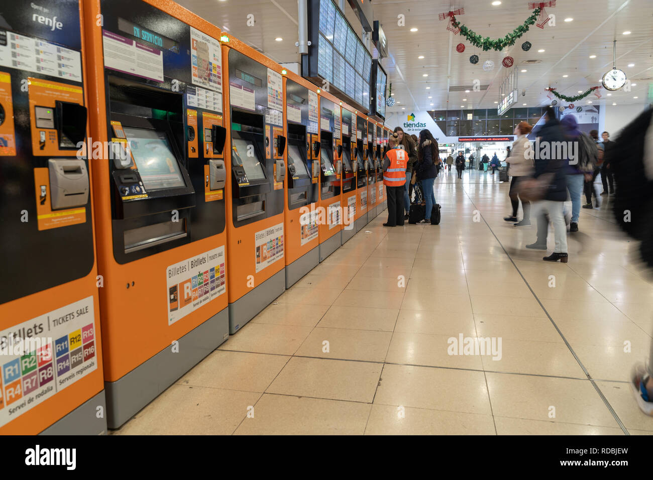 Renfe de l'hôte d'aider les voyageurs à acheter des billets dans les distributeurs automatiques de la gare Sants de Barcelone, de l'information rodalies Catalogne, Espagne Banque D'Images