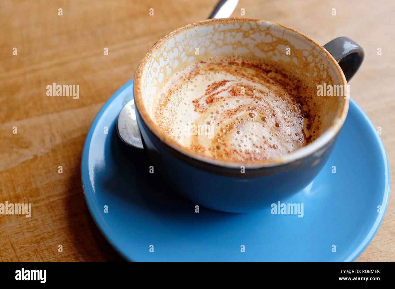 Cappuccino en bleu tasse et soucoupe sur la table de bois Banque D'Images