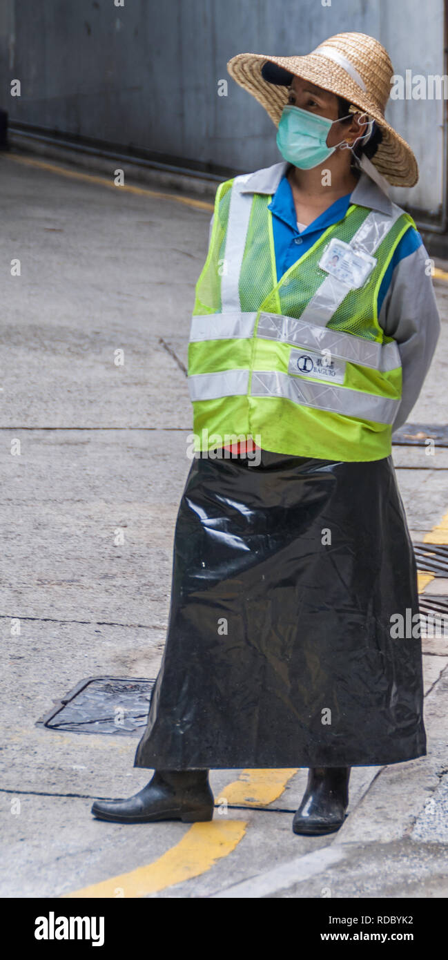 Hong Kong, Chine - 12 mai 2010 : le trafic des femmes à la sortie de parking gardien jaune fluorescent avec veste et masque de visage. Banque D'Images