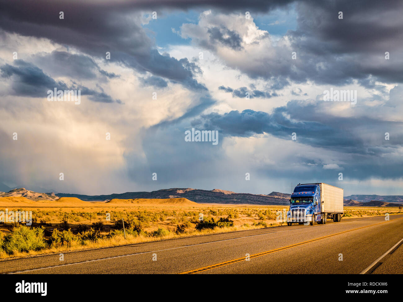 Belle vue panoramique de camion semi-remorque classique sur la route vide avec ciel dramatique dans la lumière du soir au coucher du soleil d'or Banque D'Images