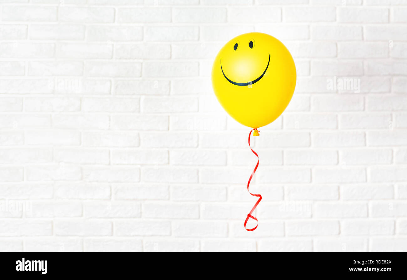 Ballon jaune avec smile raccroche aganst mur blanc Banque D'Images