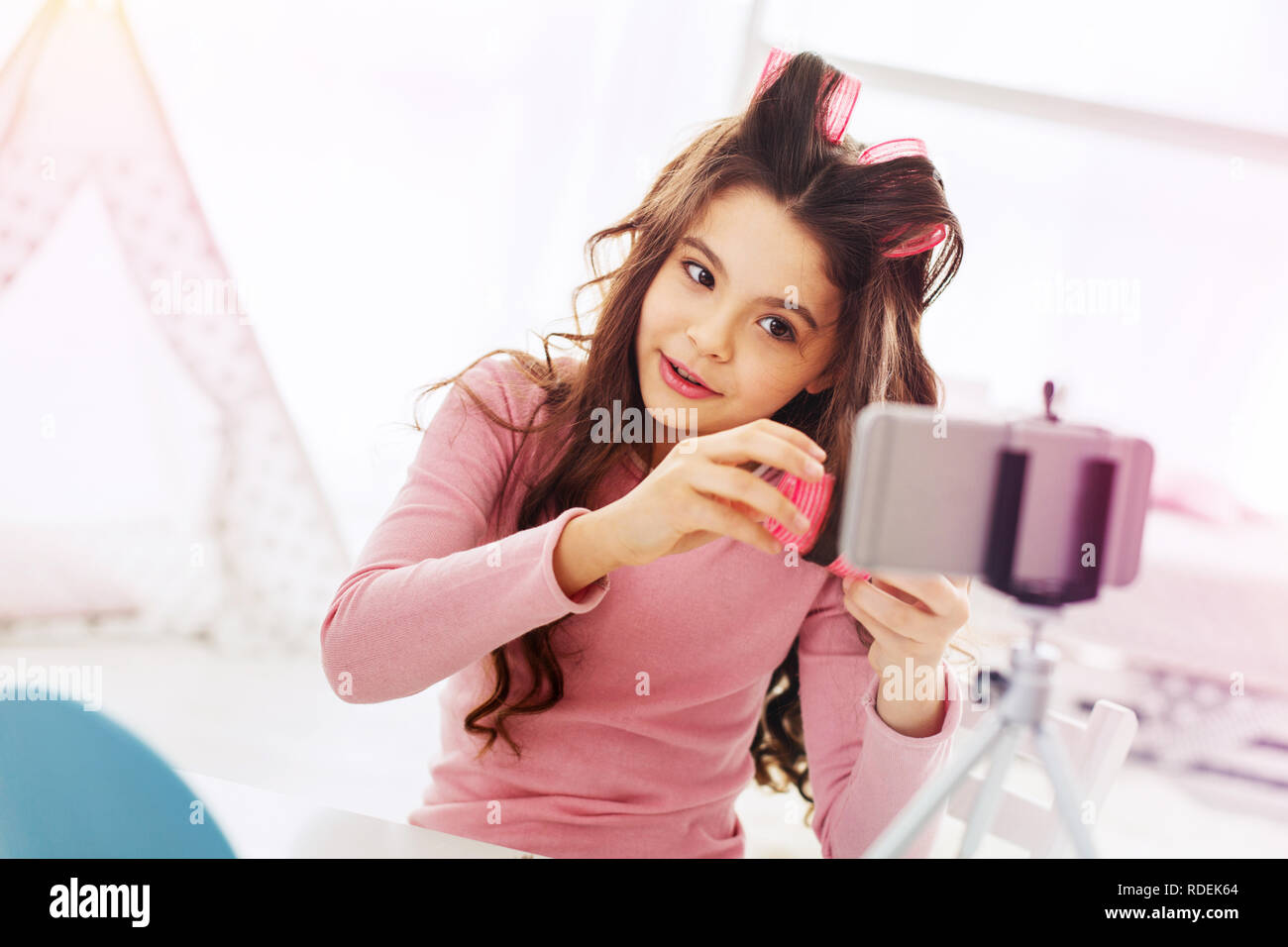 La fille aux cheveux noirs à l'aide de big pink hair curlers tout en étant prêt pour son anniversaire Banque D'Images