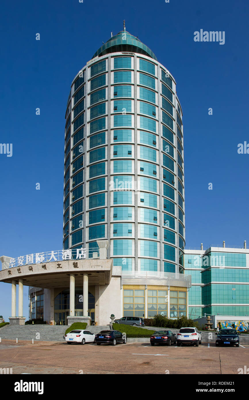 Hua un hôtel international contre un ciel bleu. Le bâtiment de forme cylindrique vert est un point de repère dans la région côtière de Yantai. Banque D'Images