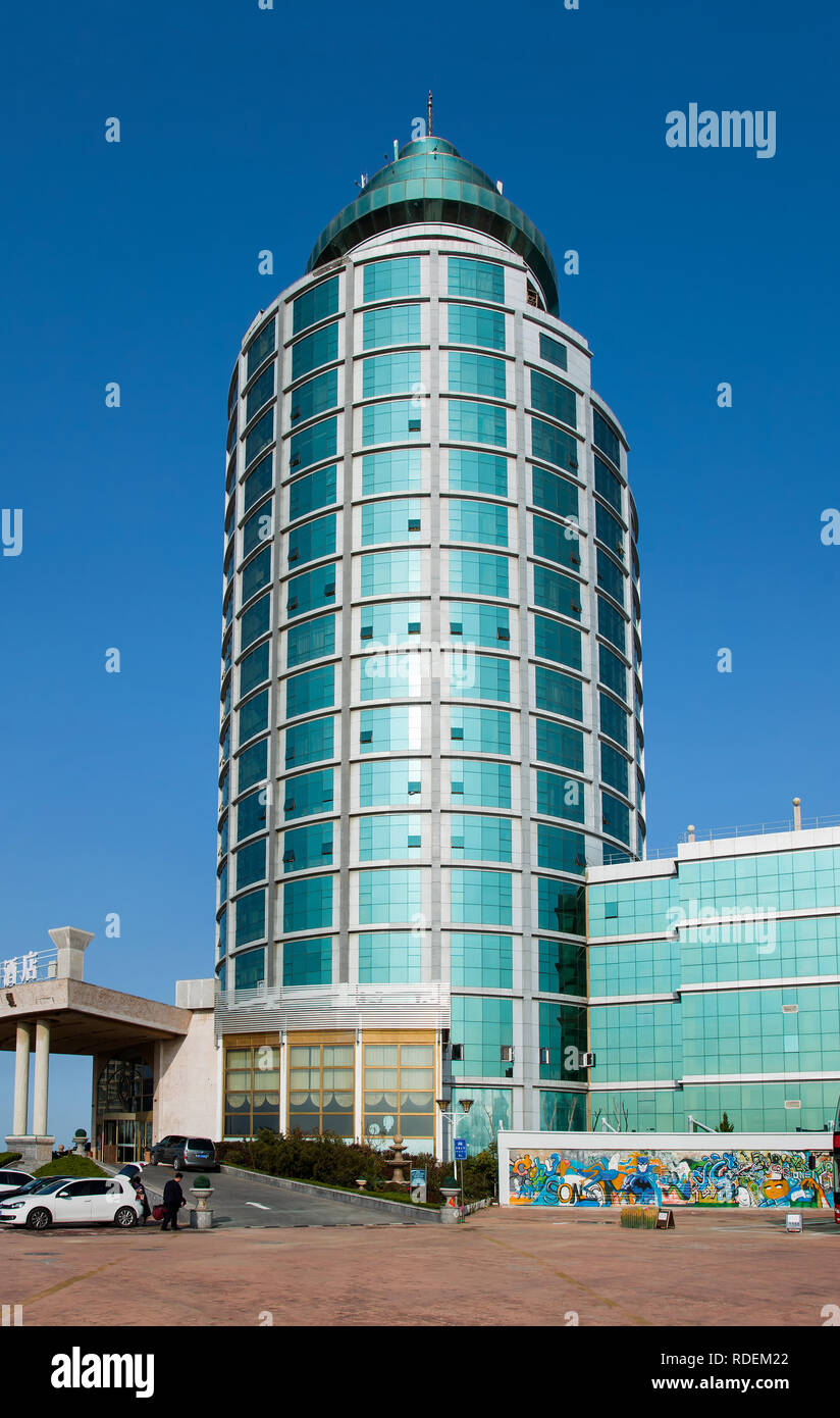 Hua un hôtel international contre un ciel bleu. Le bâtiment de forme cylindrique vert est un point de repère dans la région côtière de Yantai. Banque D'Images