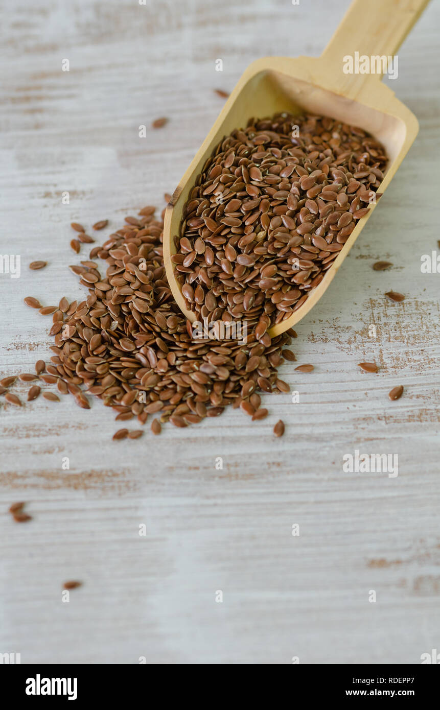 Graines de lin brun en cuillère en bois sur fond blanc. Banque D'Images