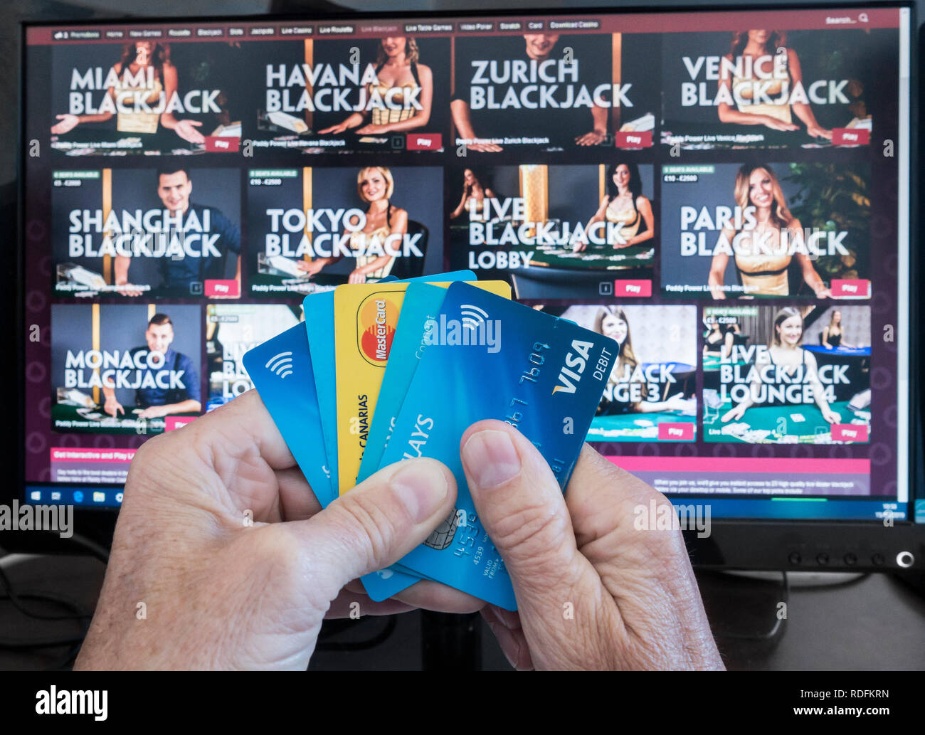 Jeu en ligne. Personne qui détient les cartes de crédit avec puissance de Paddy site sur écran/ordinateur en arrière-plan. Banque D'Images