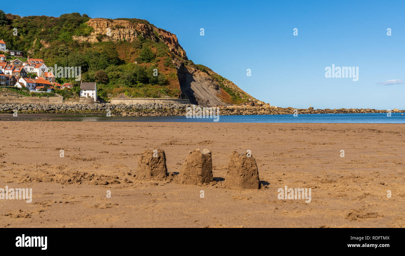 Châteaux de sable sur la plage de sables bitumineux, Runswick North Yorkshire, Angleterre Royaume-uni - Runswick Bay avec en arrière-plan Banque D'Images