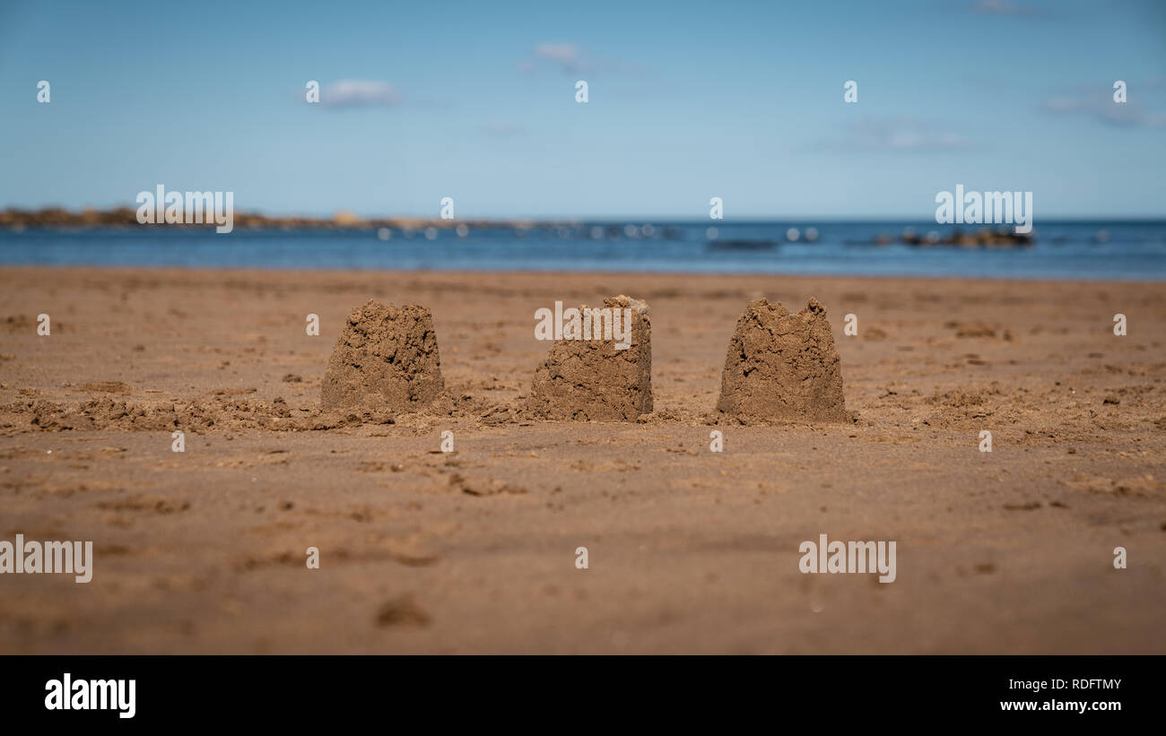 Châteaux de sable sur la plage de sables bitumineux, Runswick North Yorkshire, Angleterre Royaume-uni - avec la mer du Nord à l'arrière-plan Banque D'Images