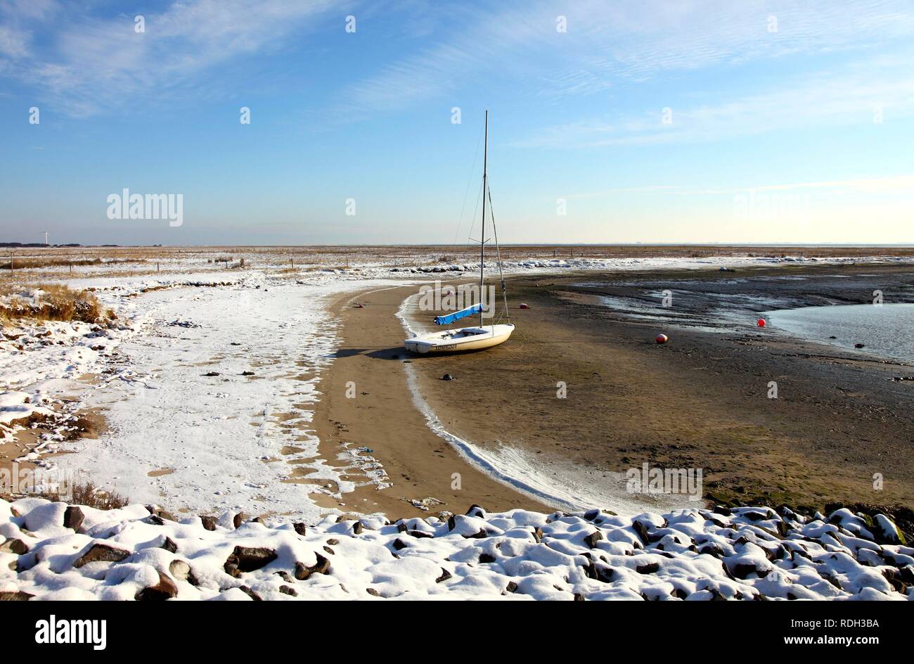 Dans la baie de la mer des Wadden avec un bateau à voile, la plage couverte de neige sur la Frise orientale Mer du Nord île de Spiekeroog, Basse-Saxe Banque D'Images