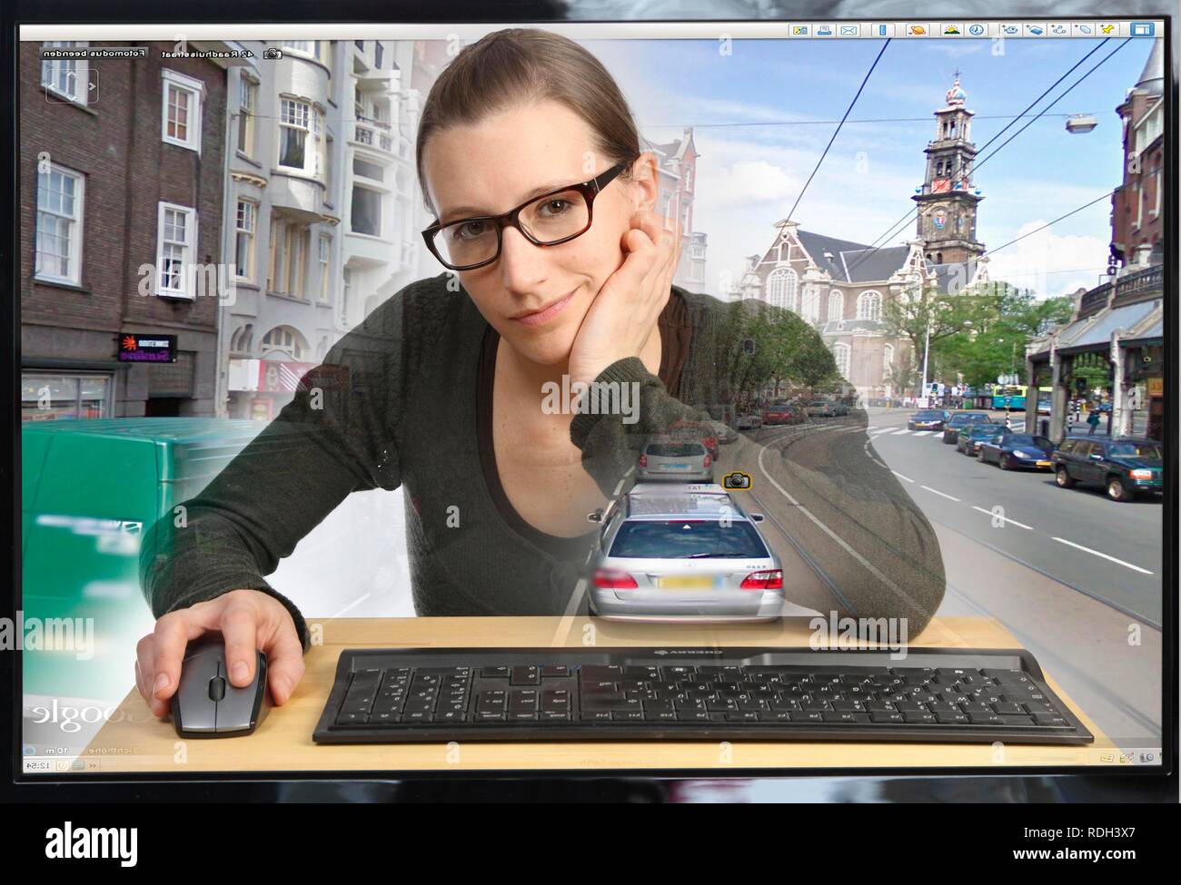 Jeune femme assise à un ordinateur à l'aide de Google Street View, la précision de l'image avec une section de la ville d'Amsterdam, les gens et Banque D'Images