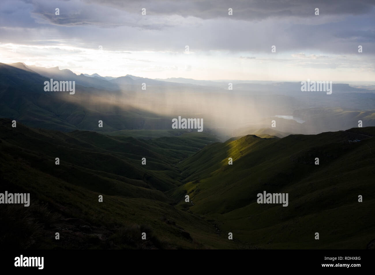 La lumière du soleil par des nuages épais à la lumière de la pluie sur une région éloignée de l'amphithéâtre du Drakensberg paysage, sentier de randonnée, NP Royal Natal, SA Banque D'Images