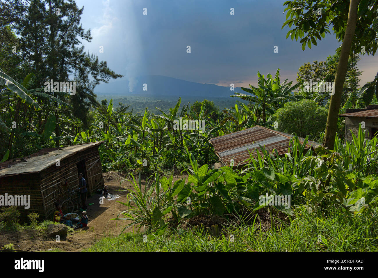 Nyamuragira, un volcan actif, éclate dans l'arrière-plan d'un village rural à l'intérieur du Parc National des Virunga, en République démocratique du Congo. Banque D'Images