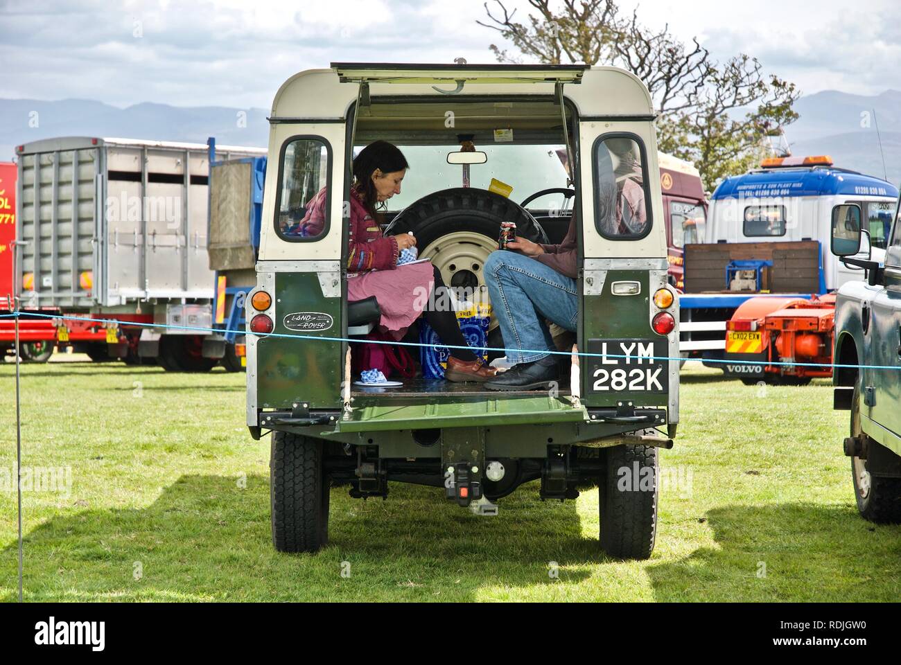 Un couple de manger leur repas à l'arrière d'un vintage 90 pouces à Land Rover l''Anglesey Vintage Rally, Anglesey, au nord du Pays de Galles, Royaume-Uni, mai 2010 Banque D'Images