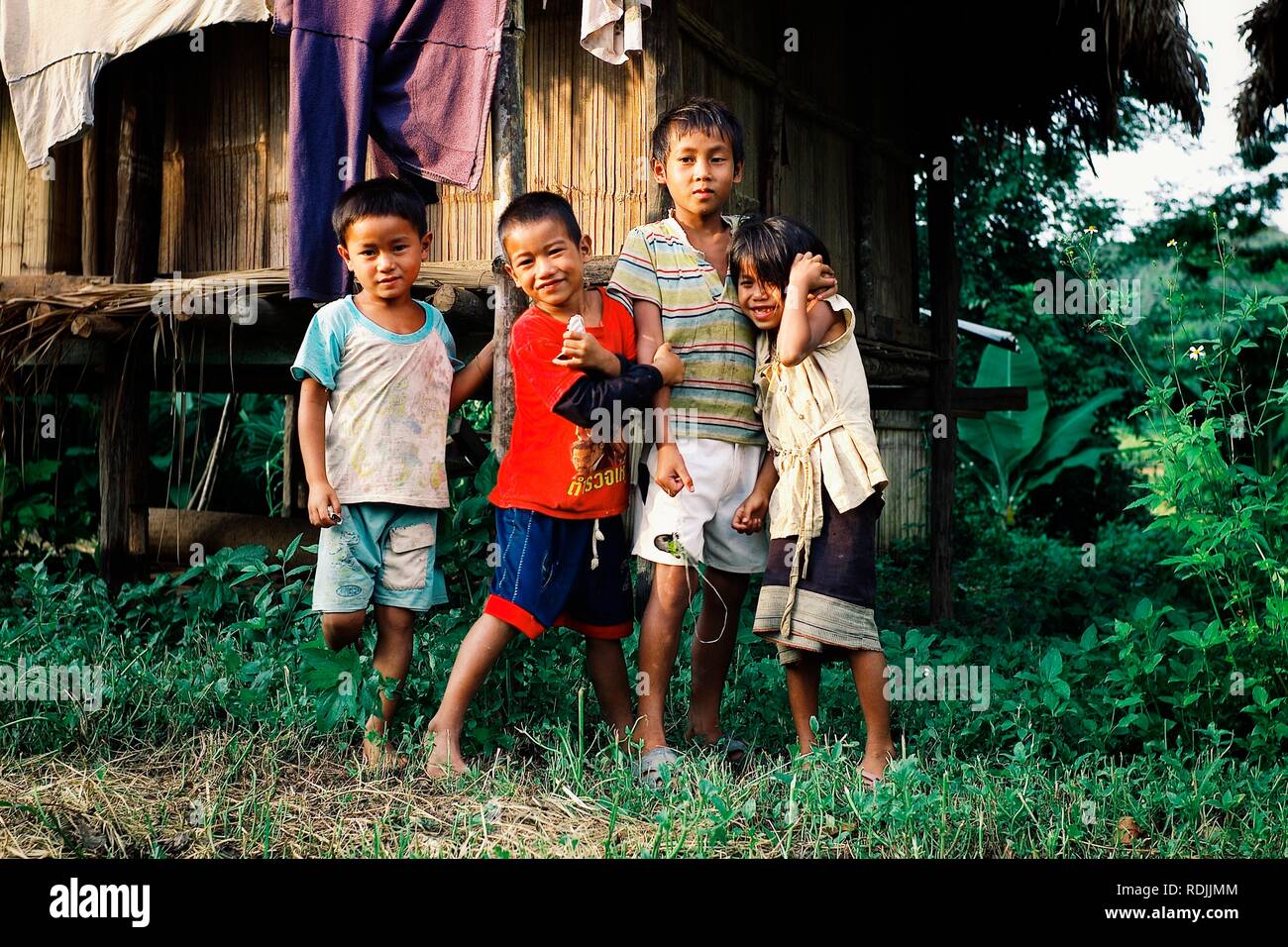 Luang Namta / Laos - 06 juil 2011 : Enfants attendant à l'extérieur de leur maison de style cabane en bambou Banque D'Images