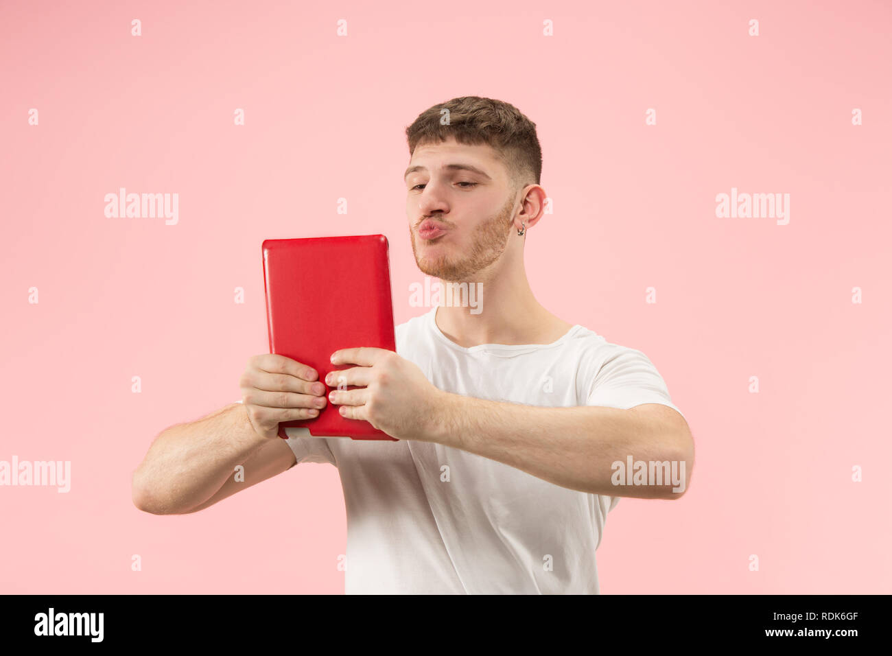 Businessman hugging ordinateur portable. L'amour à computer concept. Attractive male avant mi-longueur à la mode, portrait studio rose backgroud. Jeune homme barbu émotionnelle. Les émotions humaines, l'expression faciale concept. Banque D'Images