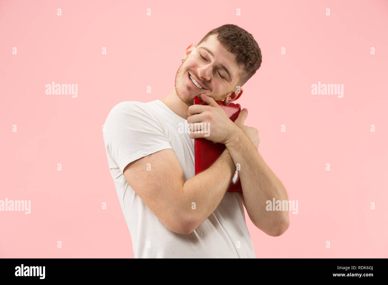 Businessman hugging ordinateur portable. L'amour à computer concept. Attractive male avant mi-longueur à la mode, portrait studio rose backgroud. Jeune homme barbu émotionnelle. Les émotions humaines, l'expression faciale concept. Banque D'Images