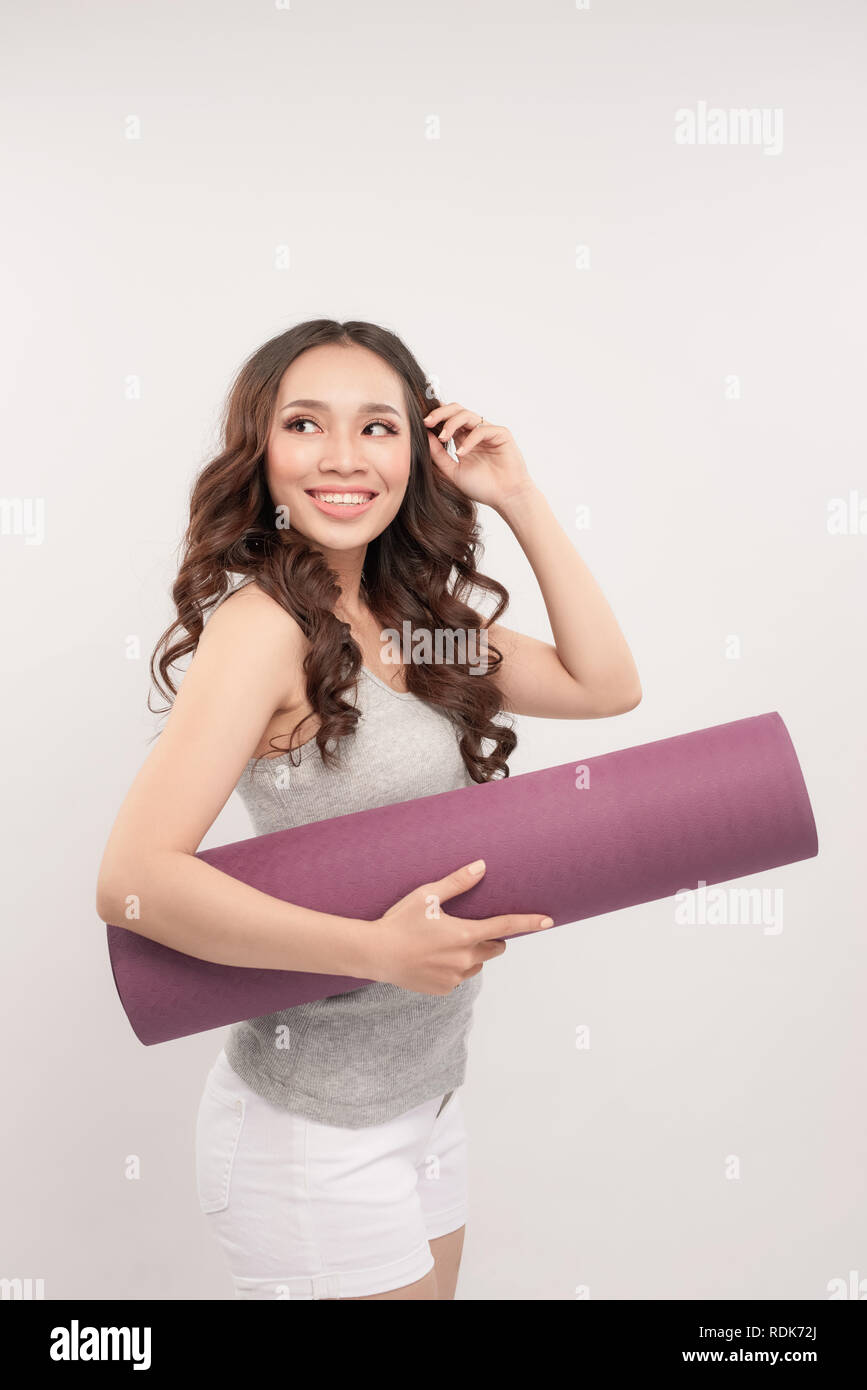 Sports Happy woman holding yoga mat sur fond gris. Jusqu'à la Banque D'Images