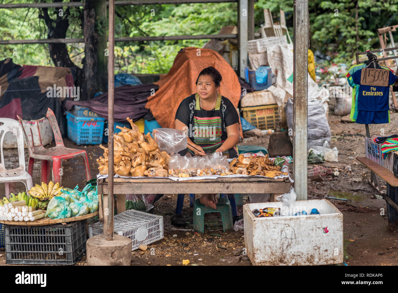 Vientiane, Laos - 9 août 2018 : une femme vend le poulet bouilli haché, des fruits et des boissons dans la rue pleine de différentes sortes de déchets. Banque D'Images